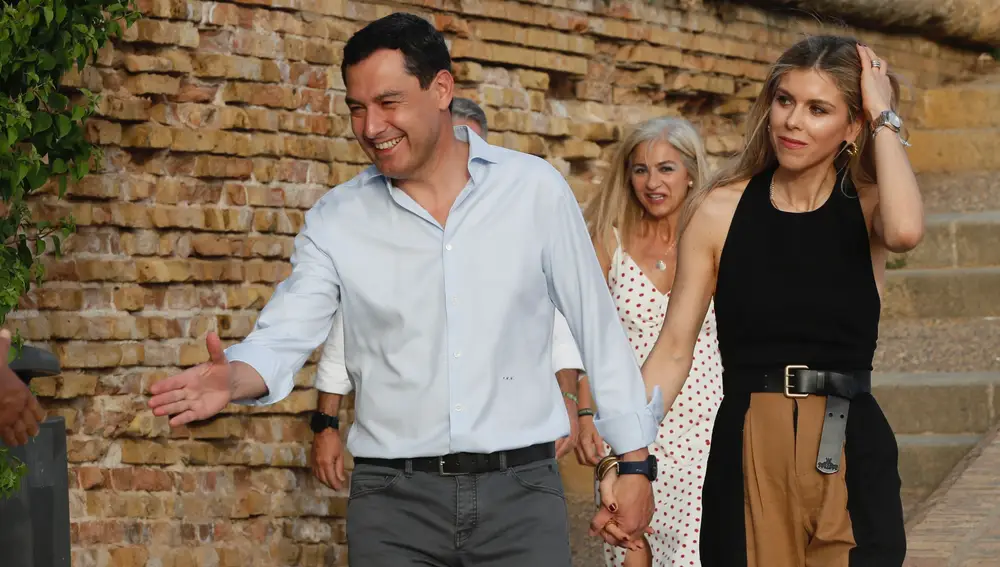 El presidente de la Junta de Andalucía y candidato a la reelección por el PP, Juanma Moreno, llega acompañado de su esposa al comienzo del acto de cierre de campaña en el Muelle de la Sal en Sevilla. EFE/José Manuel Vidal