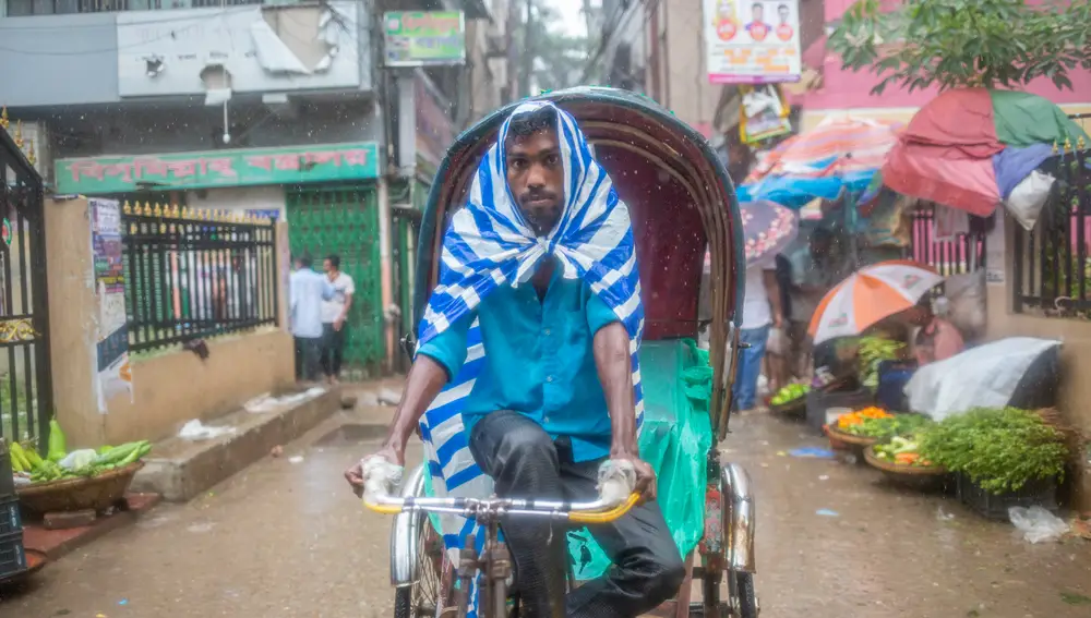 Dhaka (Bangladesh), 18/06/2022.- A rickshaw puller rides his rickshaw as he shelters himself under a plastic sheet during a rain in Dhaka, Bangladesh, 18 June 2022. Monsoon rains are expected over Bangladesh and over North Bay. The Flood Forecasting and Warning Centre warned that the floods could hit 14 districts in the northern region of Bangladesh in the next two days. (Inundaciones) EFE/EPA/MONIRUL ALAM