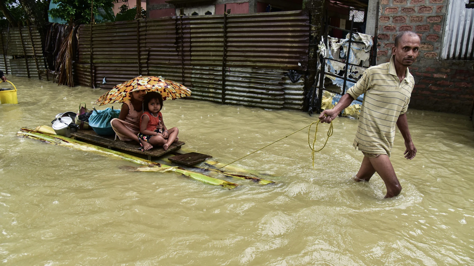 18 June 2022, India, Guwahati: A man pulls a raft with two children on the flood waters that have submerged a village in the Nalbari district. Photo: Dasarath Deka/ZUMA Press Wire/dpa Dasarath Deka/ZUMA Press Wire/dp / DPA 18/06/2022 ONLY FOR USE IN SPAIN