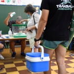 Un hombre cargado con nevera y sombrilla de playa espera para ejercer su derecho al voto en el colegio Virgen del Mar de Almería. EFE/Carlos Barba