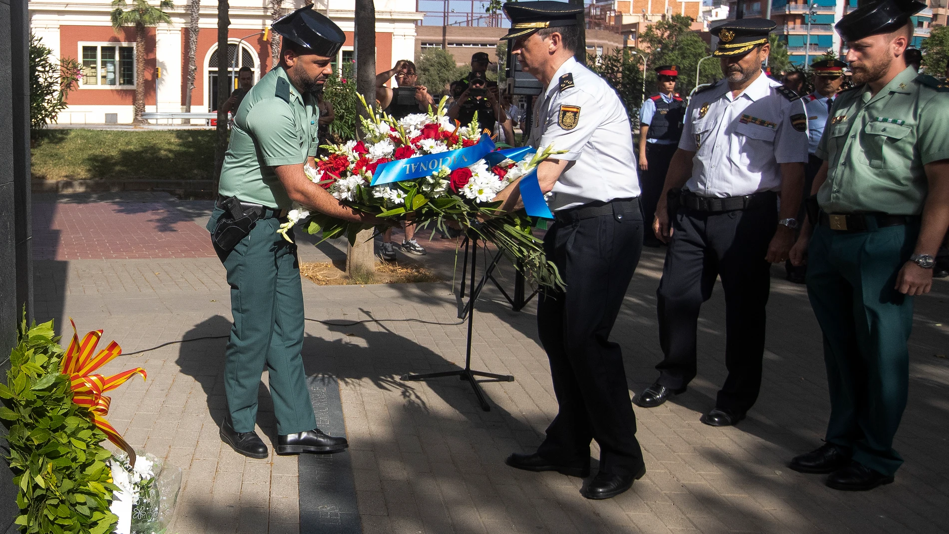 Miembros de la Guardia Civil y de la Policía Nacional colocan un ramo de flores en el monumento a las victimas del terrorismo durante el homenaje que se ha celebrado este domingo en el XXXV aniversario del atentado del Hipercor de Barcelona