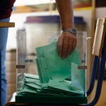 Una de las personas responsables recoge los votos de una urna para proceder al recuento de votos en un colegio de Córdoba, hoy domingo 19 de junio.