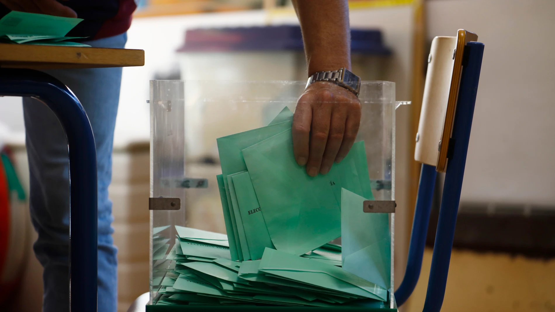 Una de las personas responsables recoge los votos de una urna para proceder al recuento de votos en un colegio de Córdoba, hoy domingo 19 de junio.