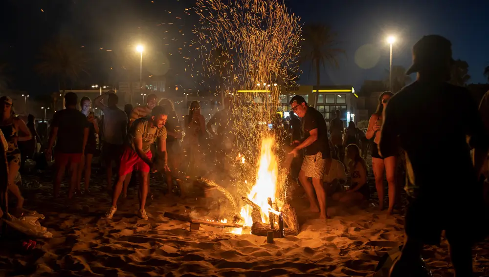 Centenares de personas frente a una hoguera en la playa de la Malvarrosa durante la Noche de San Juan