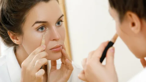 Mujer aplicando corrector de ojeras.