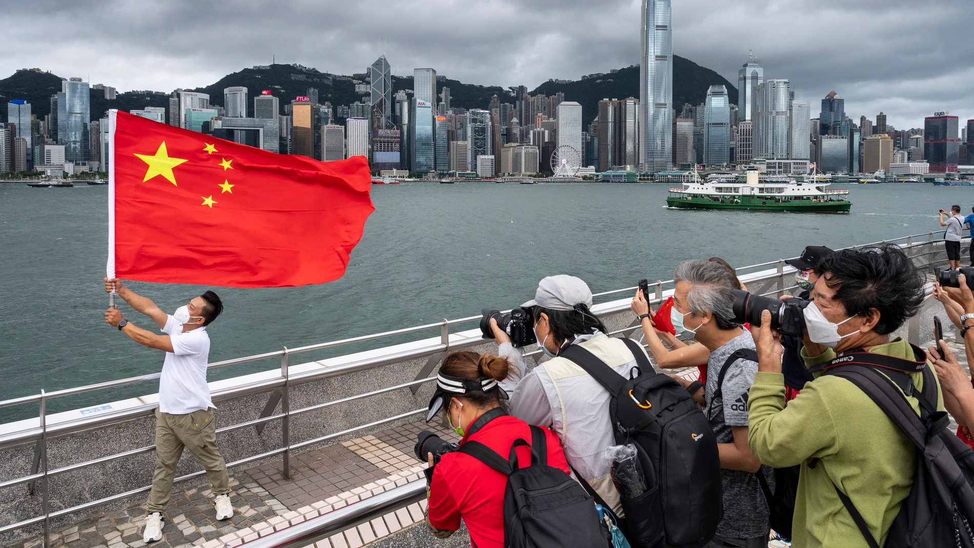 Un pobre posa con una bandera china en el Victoria Harbour de Hong Kong, en China