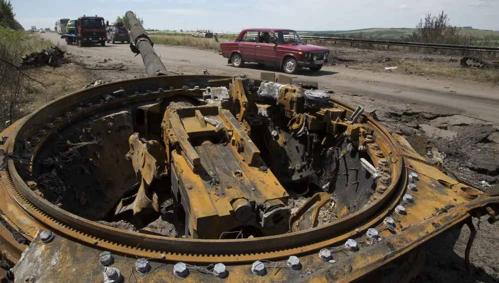 Un automóvil pasa junto a una torreta de un tanque perteneciente a la República Popular de Donetsk que se había desprendido después de una explosión, cerca de la ciudad de Slovyansk, región de Donetsk