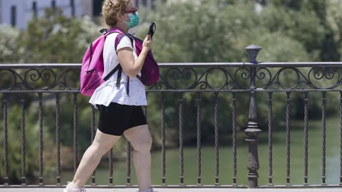 Una mujer con mascarilla cruza el puente de Triana, en Sevilla