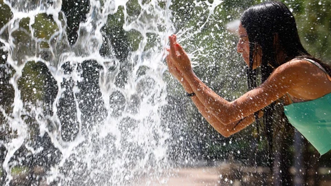 Una persona se refresca en una de las fuentes del centro de Córdoba