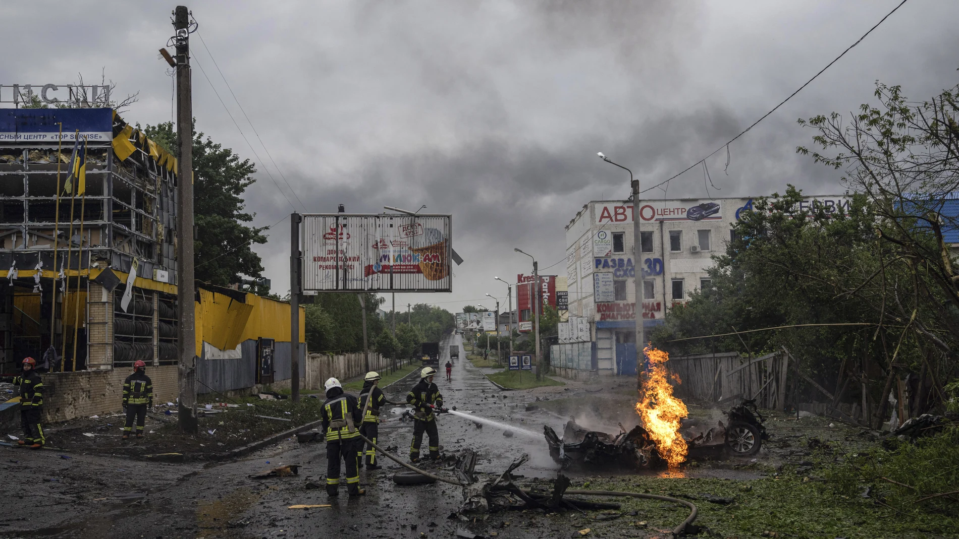 Los equipos de rescate tratan de sofocar el fuego de un automóvil destruido tras un ataque ruso en un barrio residencial en el centro de Jarkiv
