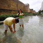 Dos jóvenes se refrescan en una fuente en los alrededores de la Judería de Córdoba