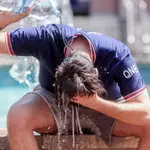 Un joven se tira una botella de agua por encima para combatir el calor