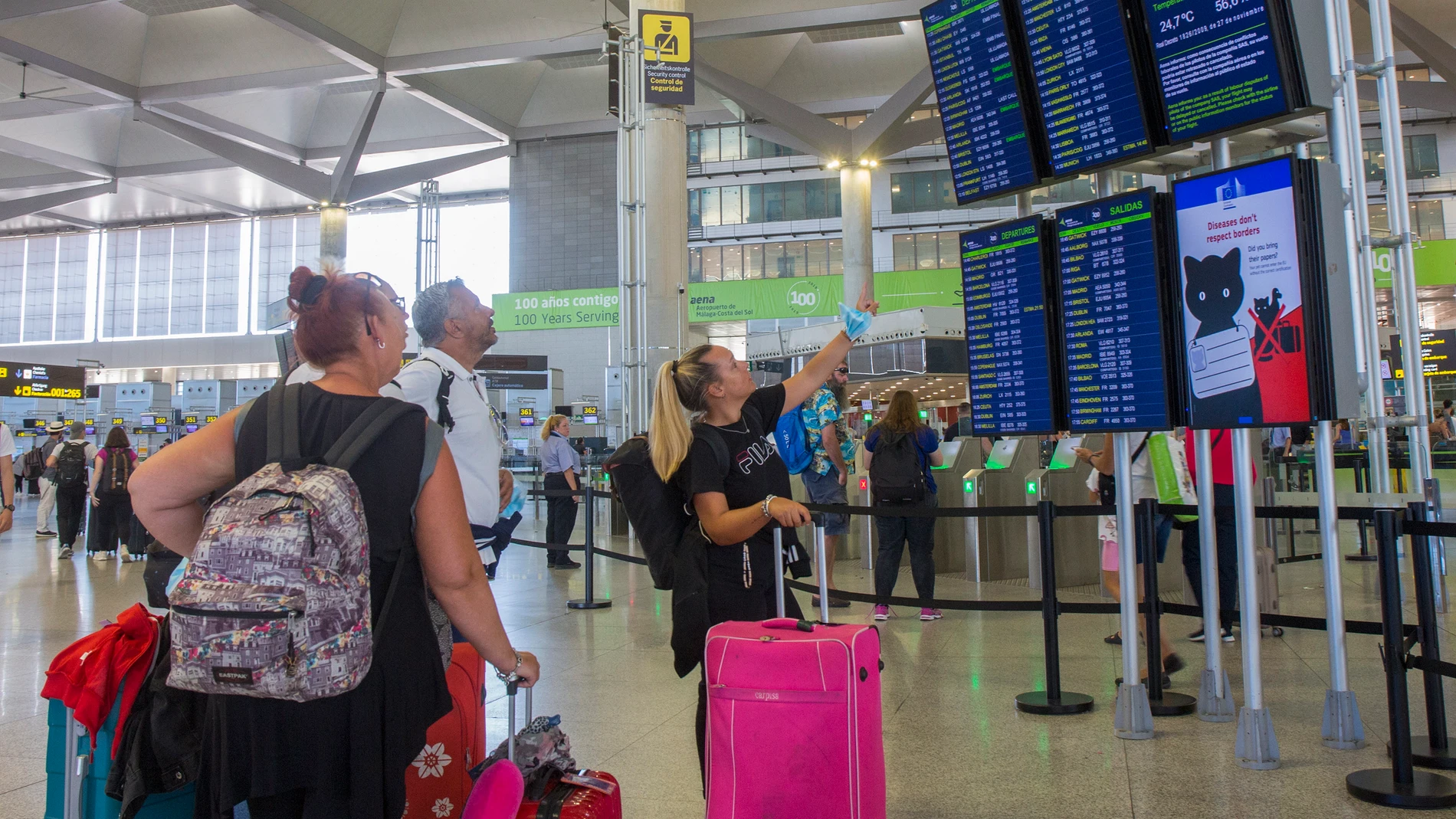 Varias personas miran los paneles informativos de los vuelos en la Terminal 3 de salidas del aeropuerto de Málaga. EFE/Álvaro Cabrera