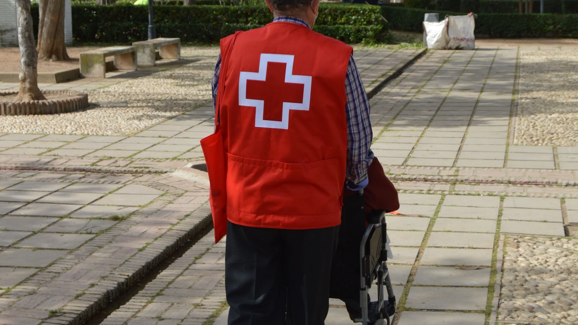 Un voluntario de la Cruz Roja acompaña a una persona mayor