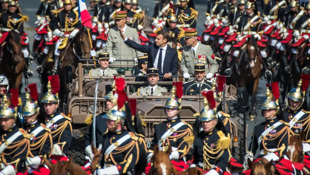 El presidente francés, Emmanuel Macron, junto al jefe del Estado Mayor, Thierry Burkhard, llega en su coche de mando rodeado de Guardias de Honor durante el desfile del Día de la Bastilla en la avenida de los Campos Elíseos en París