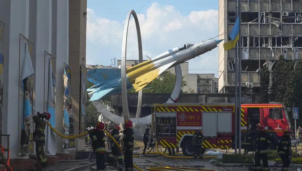 Los bomberos trabajan para extinguir un incendio en un edificio dañado por los bombardeos junto a un avión de combate soviético MiG-21, un monumento en honor a las Fuerzas Aéreas de Ucrania, en Vinnytsia, Ucrania,