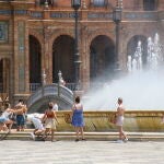 Varios turistas se refrescan en la fuente de la Plaza de España de Sevilla. EFE/ Raúl Caro.