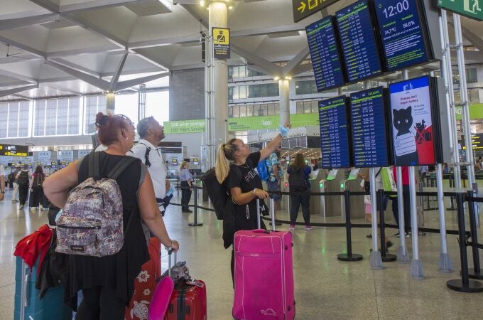 Varias personas miran los paneles informativos de los vuelos en la Terminal 3 de salidas del aeropuerto de Málaga. EFE/Álvaro Cabrera