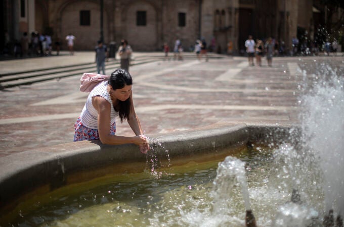 Una mujer se refresca en una fuente del centro histórico de Valencia