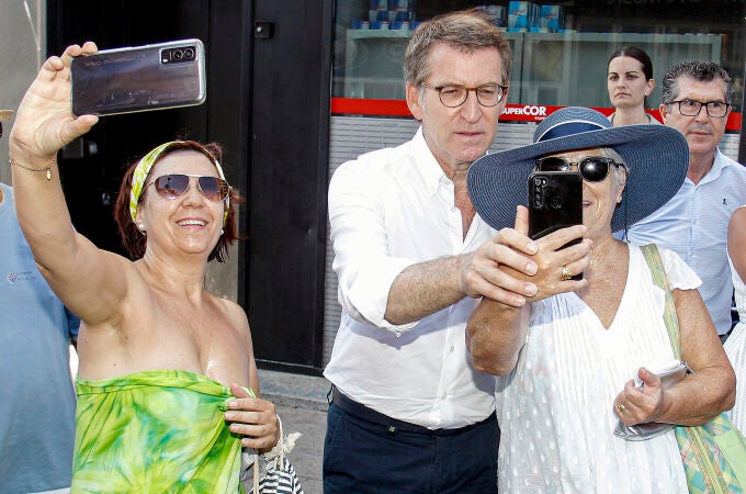El presidente del Partido Popular, Alberto Núñez Feijóo, se fotografiía con dos turistas este viernes en Benidorm donde se ha reunido con representantes del sector turístico
