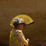 Una mujer se protege del intenso sol con un abanico en Córdoba, este sábado al mediodía