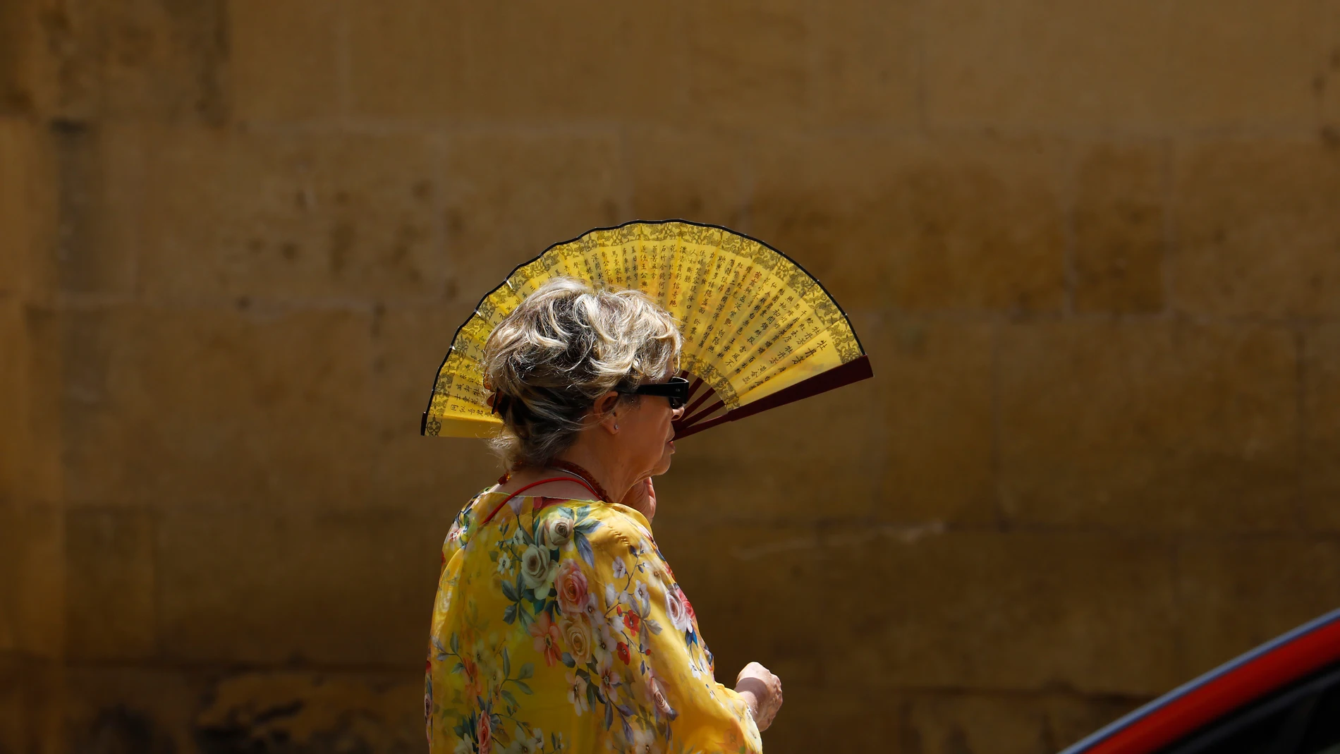 Una mujer se protege del intenso sol con un abanico en Córdoba, este sábado al mediodía