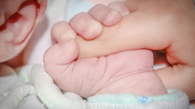 Fotografía de la mano de un bebé agarrando un dedo