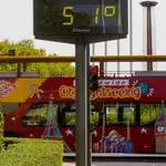Un autobús turístico pasa sin pasajeros delante de un termómetro que marca 51º en otro día con altas temperaturas en la capital andaluza a 25 de julio del 2022 en Sevilla (Andalucía, España)