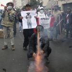 Manifestantes queman una foto del presidente Pedro Catillo cerca del Congreso en Lima
