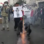 Manifestantes queman una foto del presidente Pedro Catillo cerca del Congreso en Lima