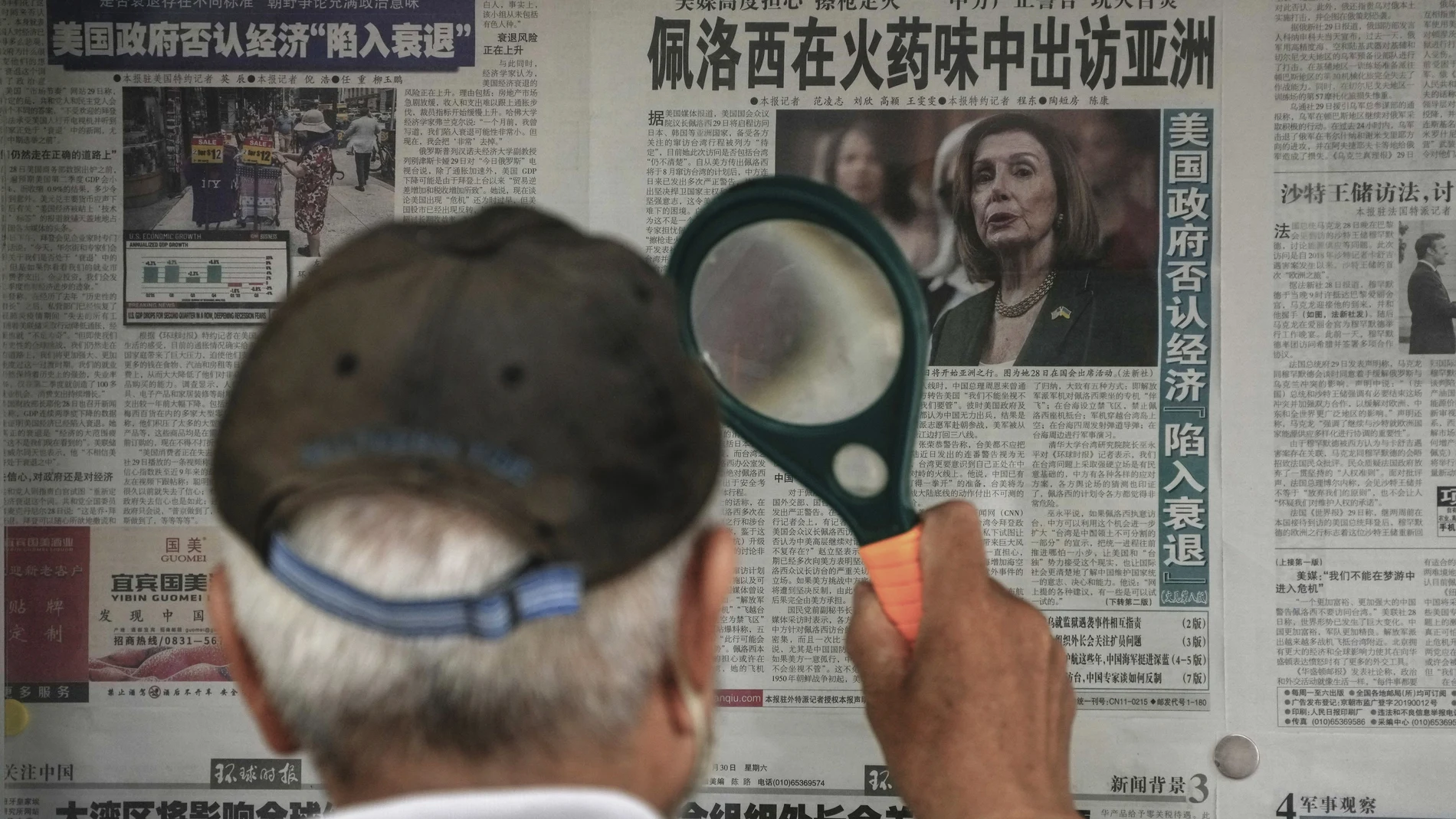 Un hombre lee con una lupa en Pekín una noticia sobre Nancy Pelosi