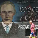 Un hombre pasa junto a un mural de Vladimir Putin en una calle de Belgrado donde se lee «Kosovo es Serbia»