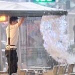 Un joven descarga el agua de los toldos tras una tormenta de agua
