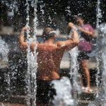 Un hombre se hace fotos mientras mitiga el calor en una fuentes de un parque de Alicante.