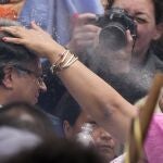 Una mujer indígena escupe agua sobre la cabeza del presidente electo Gustavo Petro, durante una ceremonia de investidura "popular y espiritual" presidida por grupos indígenas locales y activistas feministas, en Bogotá