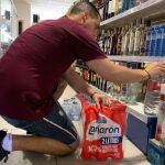 Juan Fernández, gestor de la única tienda de Puerto Moral (Huelva), repone las botellas de agua en las estanterías de su local