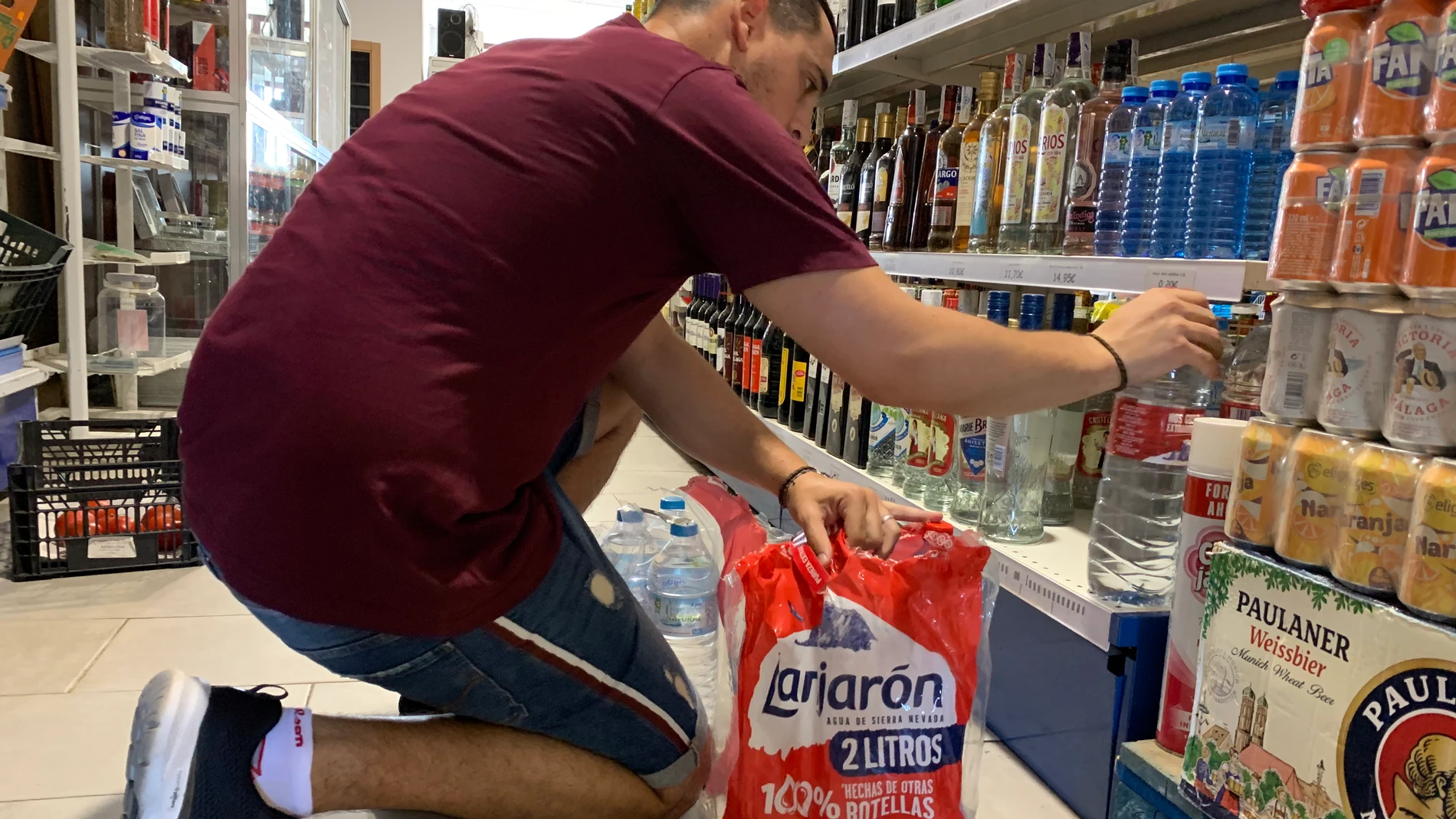 Juan Fernández, gestor de la única tienda de Puerto Moral (Huelva), repone las botellas de agua en las estanterías de su local