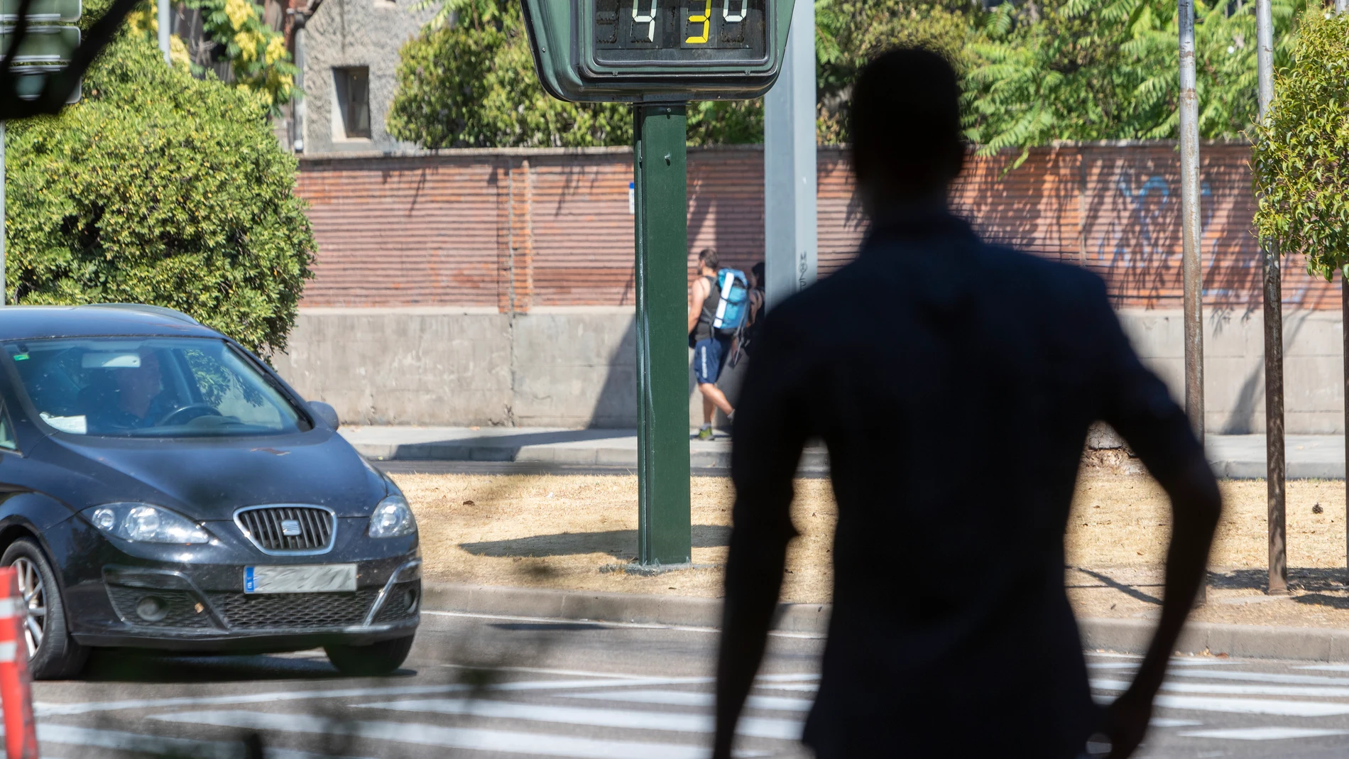 Un hombre camina con un termómetro al fondo que marca 43 grados