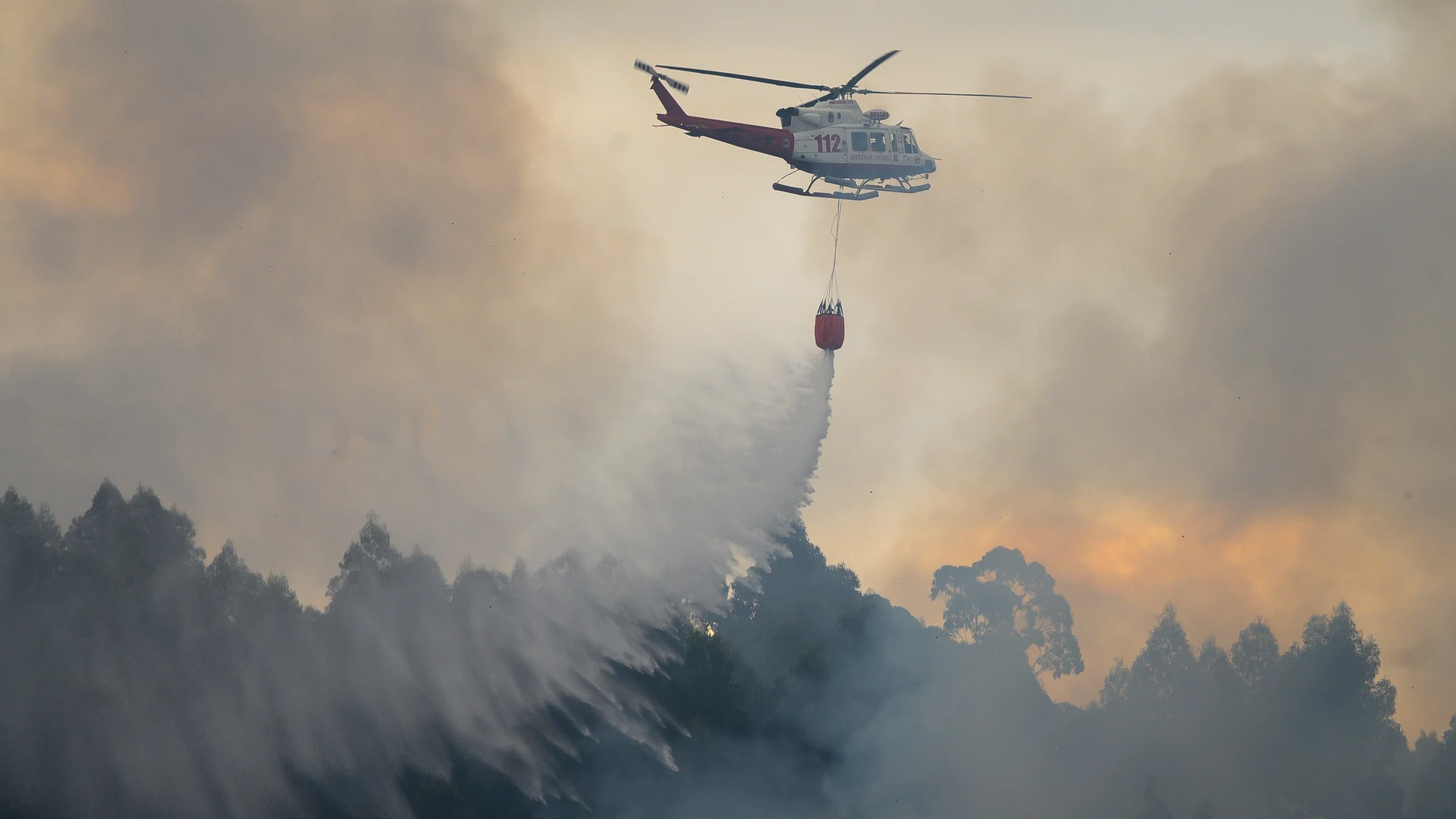 El helicóptero del 112 durante los trabajos de extinción del incendio forestal declarado en la localidad cántabra de Hazas de Cesto