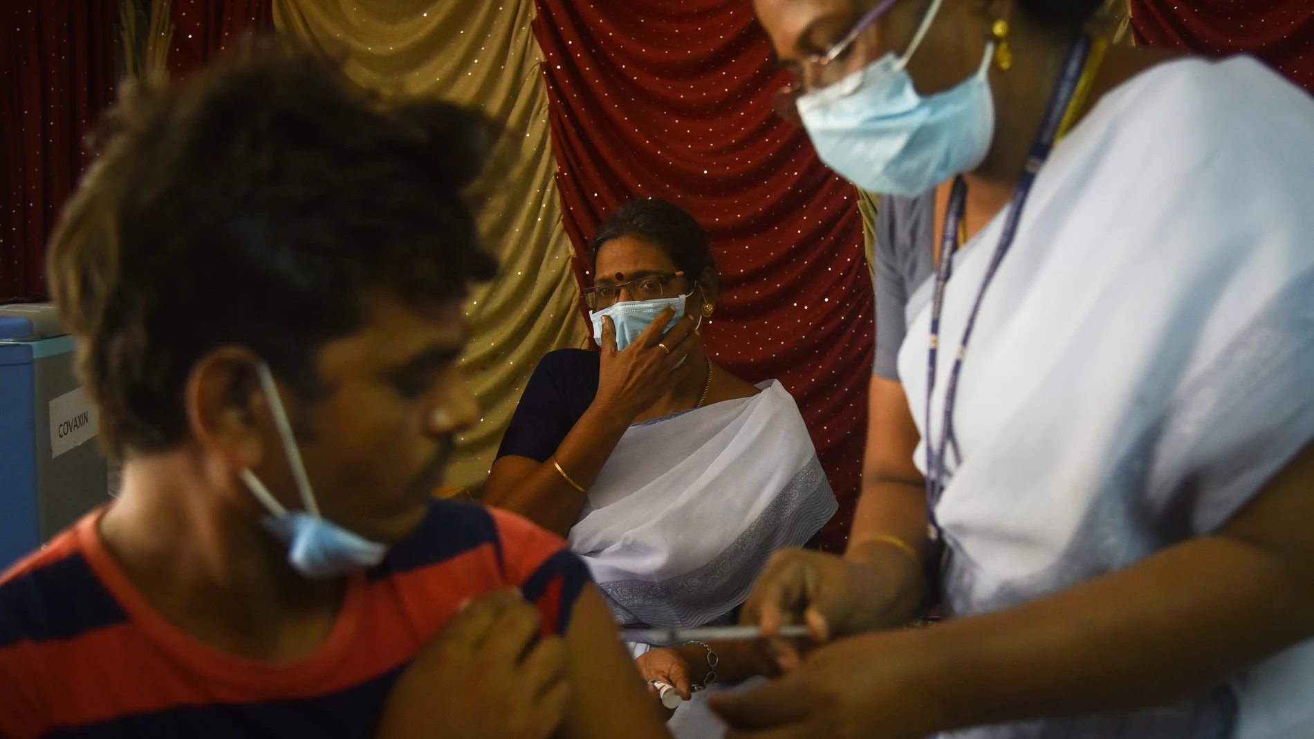 Un sanitario vacunando a un hombre frente a la covid en Chennai, India, a 12 de agosto de 2022