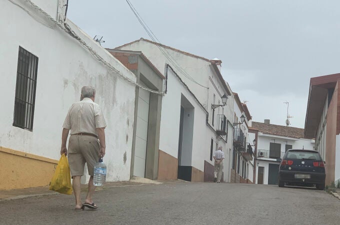 Un vecino de Cumbres Mayores (Huelva) transporta una botella de agua para consumir en su casa. EFE/Fermín Cabanillas