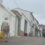 Un vecino de Cumbres Mayores (Huelva) transporta una botella de agua para consumir en su casa. EFE/Fermín Cabanillas