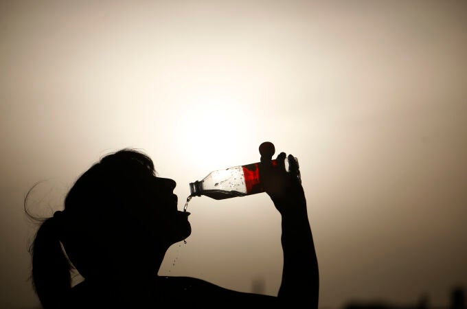 Una turista bebe agua para aliviar el intenso calor mientras pasea por el puente romano de Córdoba d