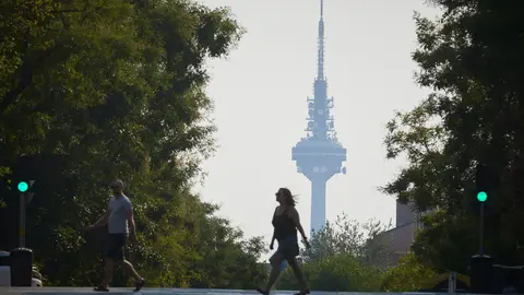Ciudadanos pasan con el pirulí de fondo por una de las calles de Madrid con el ambiente de neblina debido a los incendios de Portugal. El centro de emergencias 112 de la Comunidad de Madrid ha recibido a lo largo de la mañana de este martes 360 llamadas de ciudadanos alertados por olor a incendio y humo en diferentes puntos de la región, un hecho que se debe a un incendio activo en Portugal.