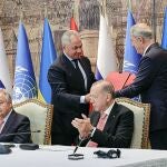 El presidente turco Recep Tayyip Erdogan, a la derecha, y el secretario general de la ONU, Antonio Guterres, se sientan mientras el ministro de Defensa ruso Sergei Shoigu, arriba a la izquierda, y el ministro de Defensa turco Hulusi Akar, arriba a la derecha, intercambian documentos durante una ceremonia de firma en el Palacio de Dolmabahce en Estambul, Turquía, el viernes 22 de julio de 2022.