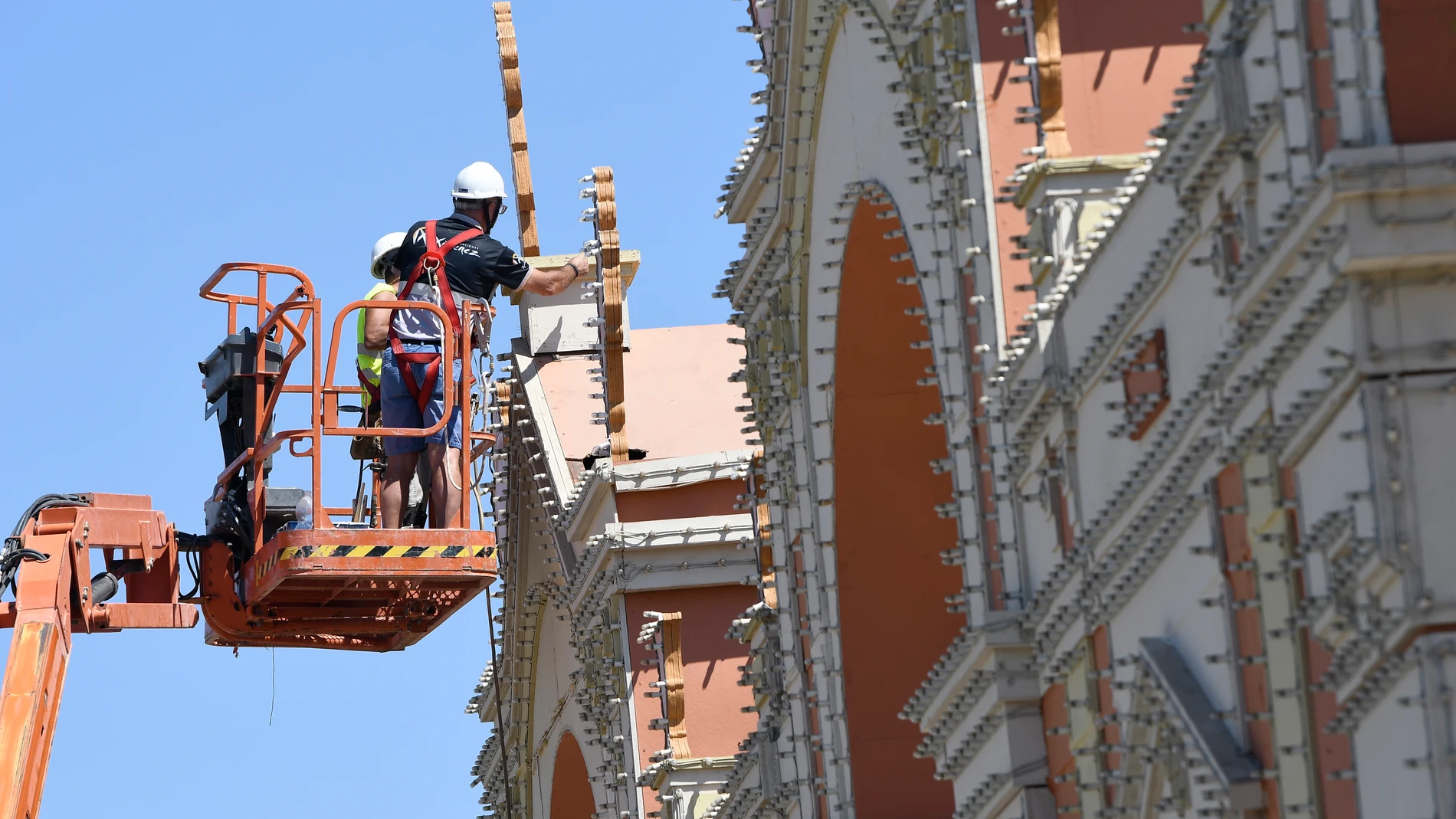 Unos operarios ultiman el montaje del alumbrado en la portada ubicada en el recinto ferial de Almería