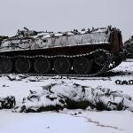 Un soldado muerto yace sobre la nieve en Járkov junto a un carro de combate incendiado