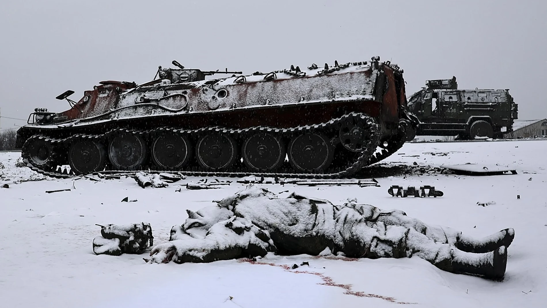 Un soldado muerto yace sobre la nieve en Járkov junto a un carro de combate incendiado