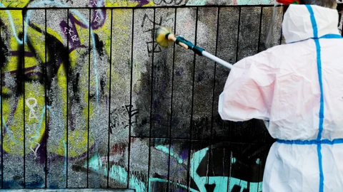 Un operario limpia una pared de los grafitis pintados con motivo de la puesta en marcha de las ‘patrullas antigrafiti