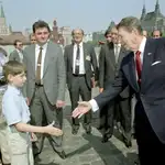 Ronald Reagan le da la mano a un niño mientras Mijaíl Gorbachov (der.) observa y el joven rubio (izq.) podría ser Vladimir Putin (izq.) espiando al presidente de EE UU